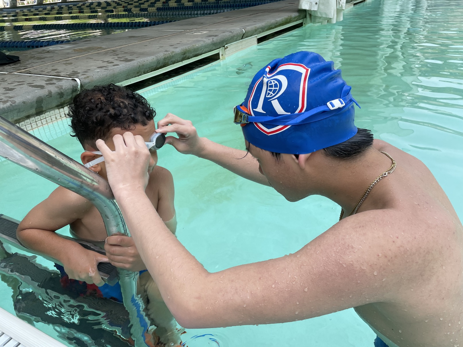 An instructor adjusting a child's swim goggles
