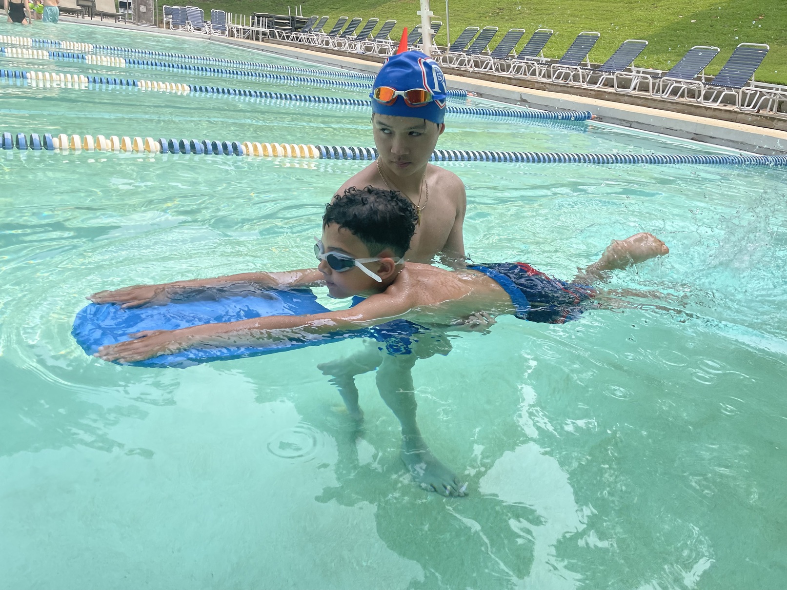 An instructor teaching a child to swim with a kickboard