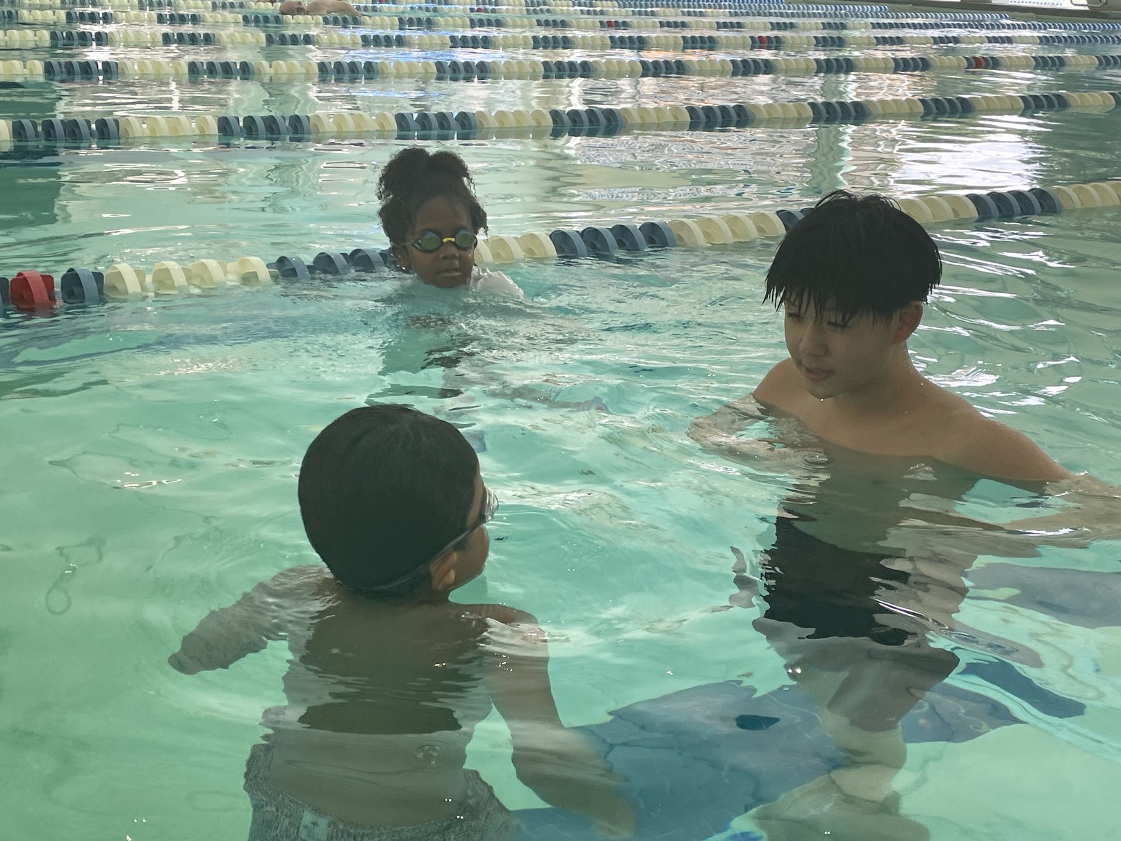 An instructor teaching a group of children to swim